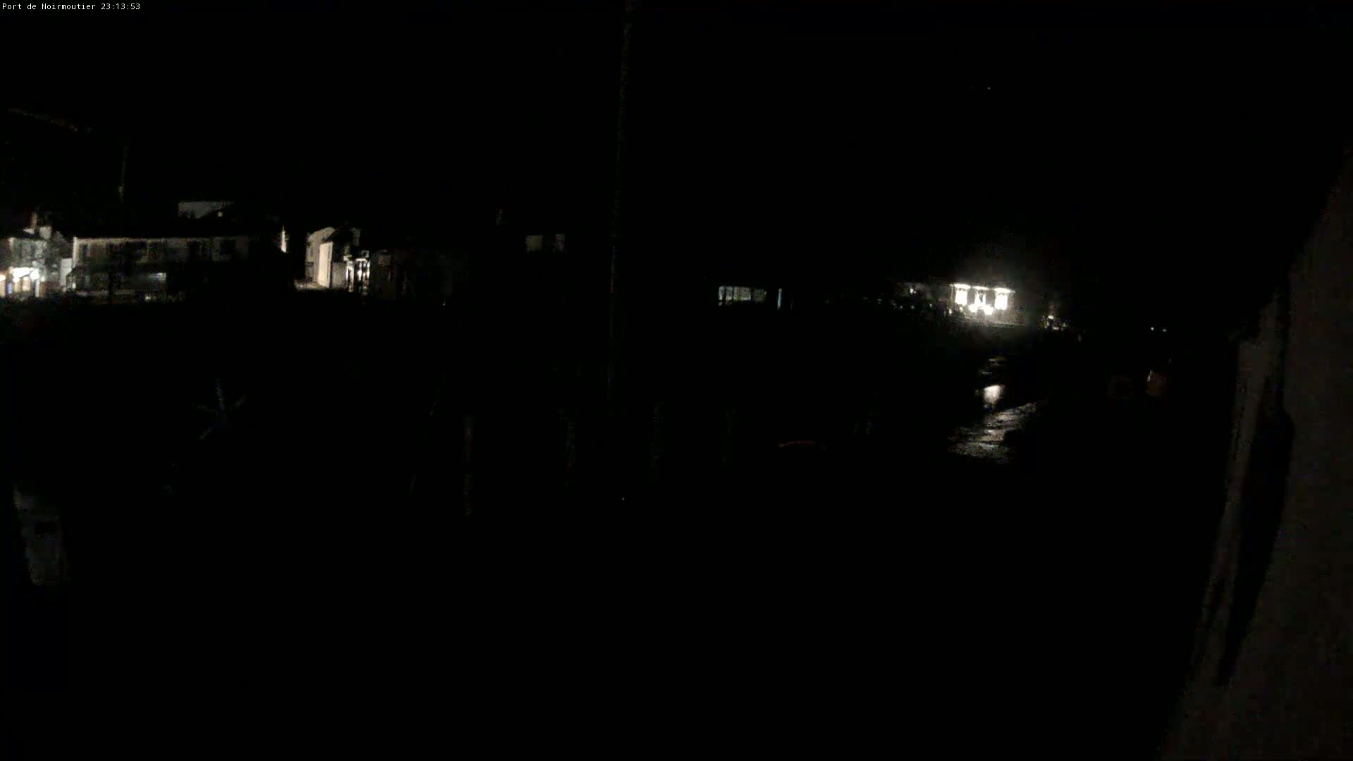 A dimly lit, nighttime scene shows dark buildings and a wet, reflective surface in the foreground.