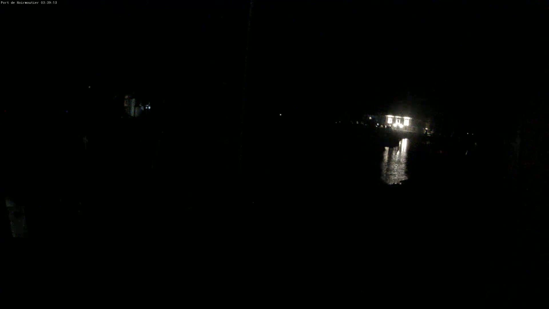 A dimly lit structure is visible across a dark body of water at night.