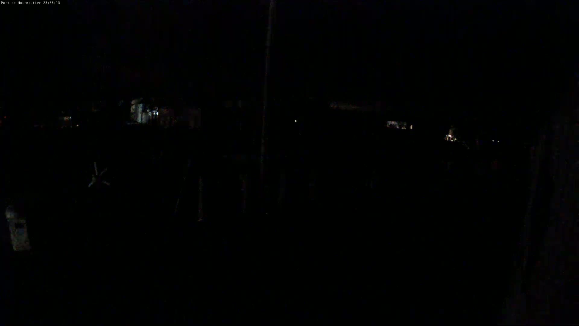 The image shows a very dark, nighttime outdoor scene with a few faint lights visible in the distance.