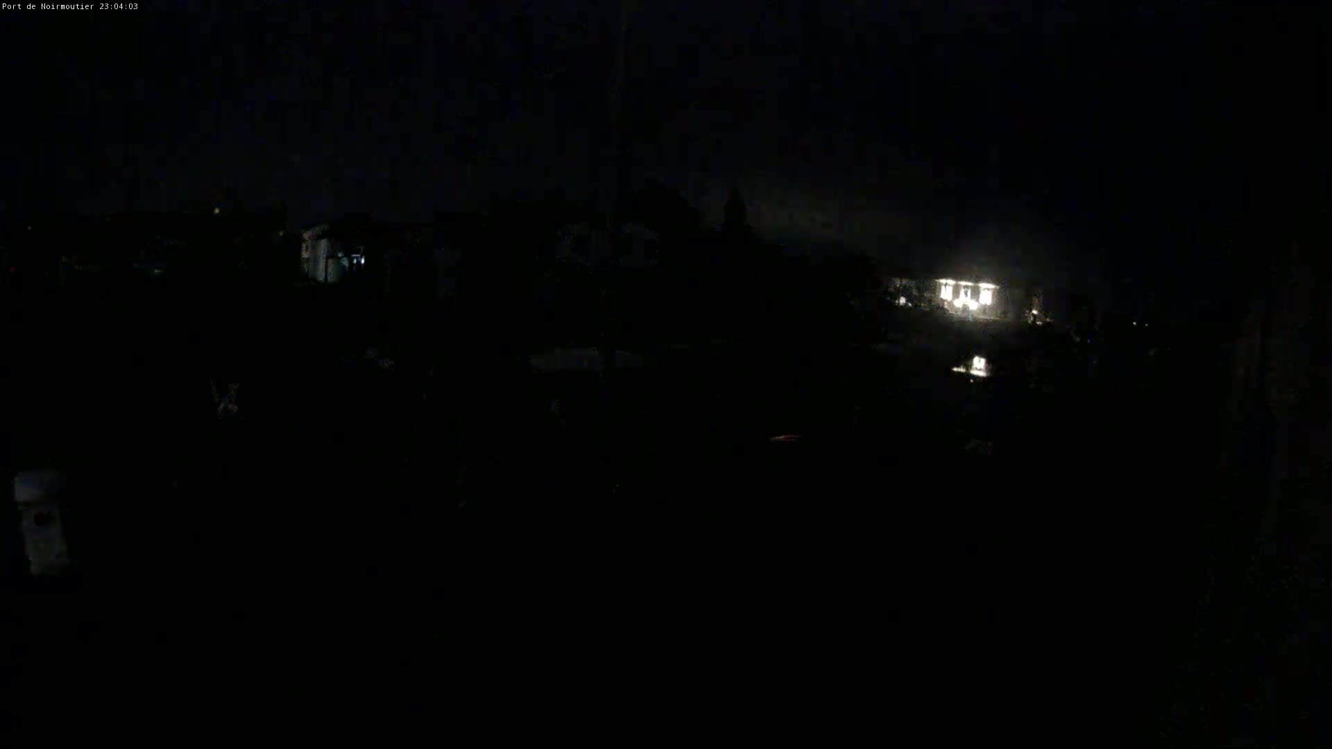 A dark, nighttime scene shows dimly lit buildings in the distance under a mostly clear sky.