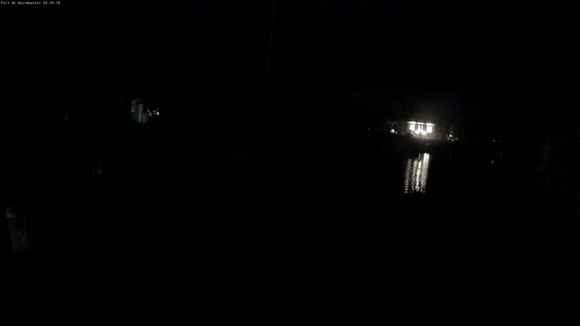 A dimly lit structure is visible across a dark body of water at night.