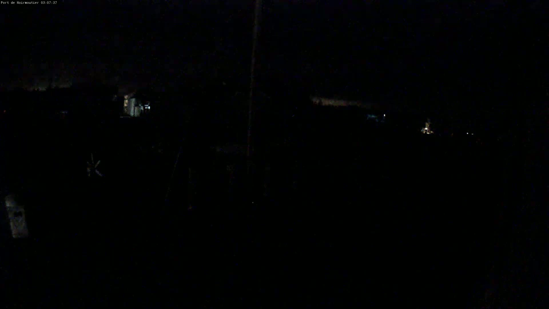 A dark, nighttime outdoor scene shows a few distant, faint lights against a mostly black sky.