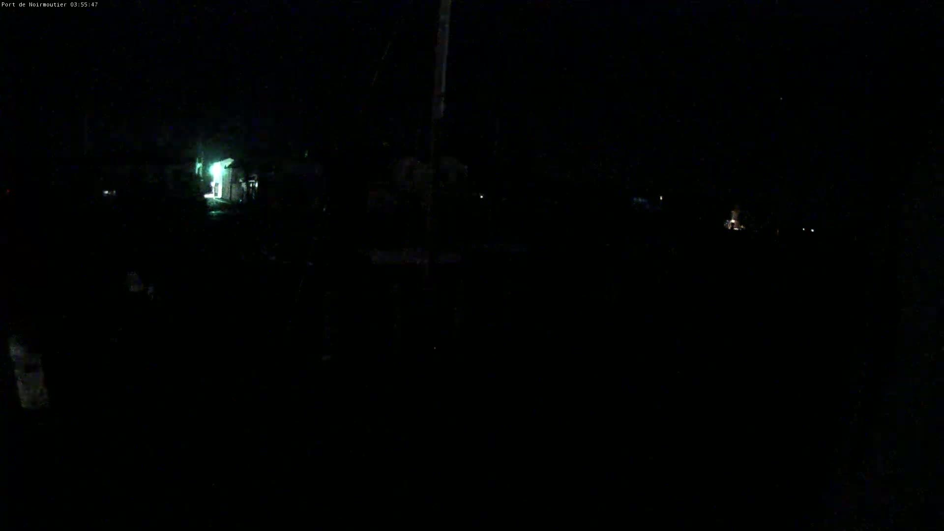 A dark, nighttime scene shows indistinct shapes and faint lights in the distance.