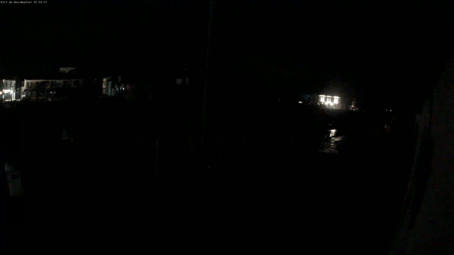 A dark, nighttime scene shows faintly lit buildings in the distance and a small, brighter area that may be a streetlight or vehicle lights closer to the viewer.