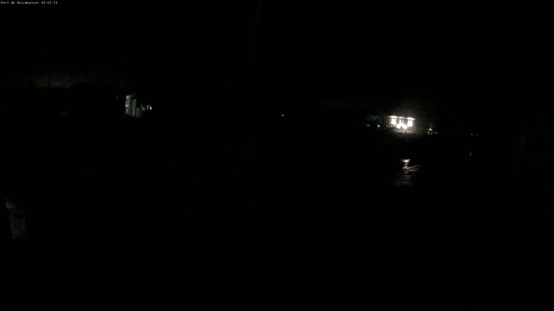A dark, nighttime scene shows a dimly lit structure in the distance.
