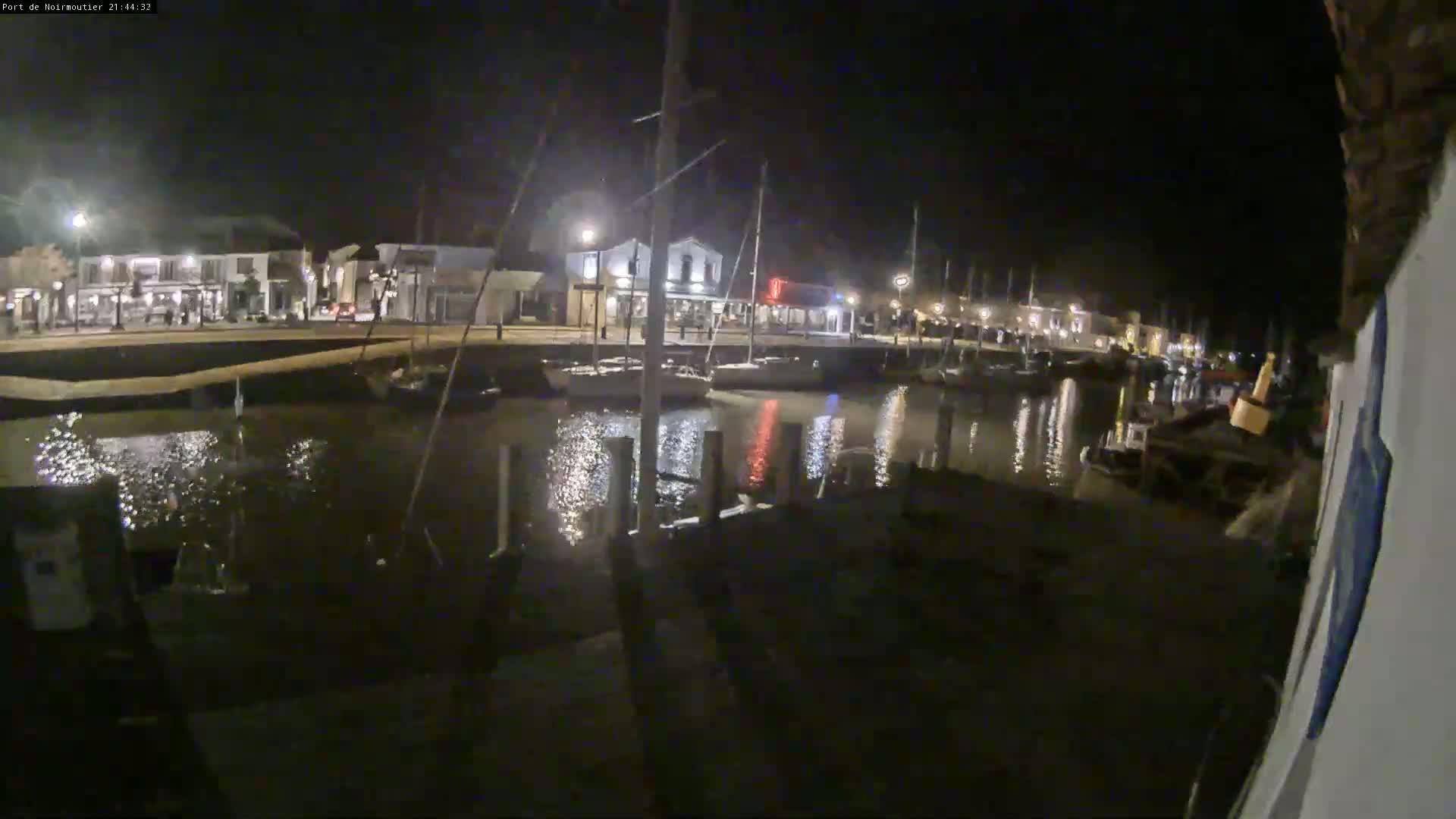 A nighttime view of a harbor with boats docked along a waterfront lined with buildings.