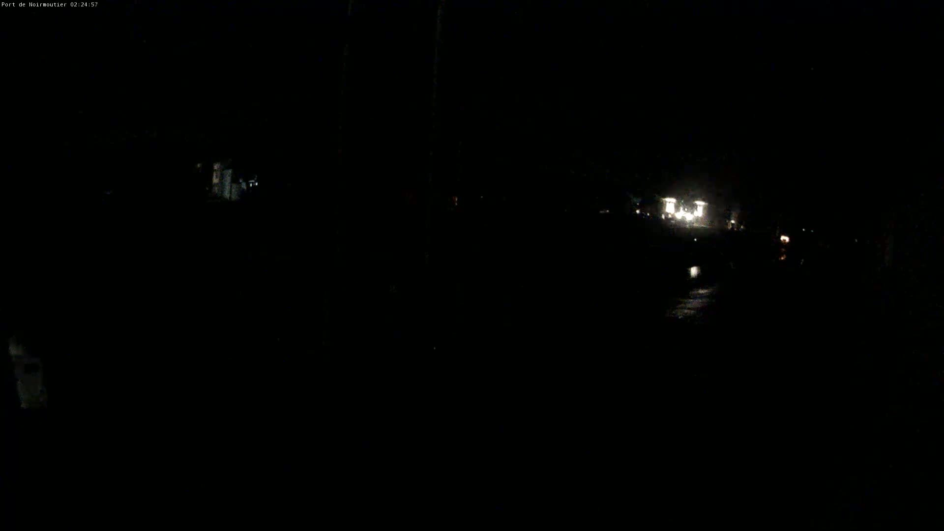A dark, nighttime scene shows faint lights in the distance, possibly from buildings or vehicles.