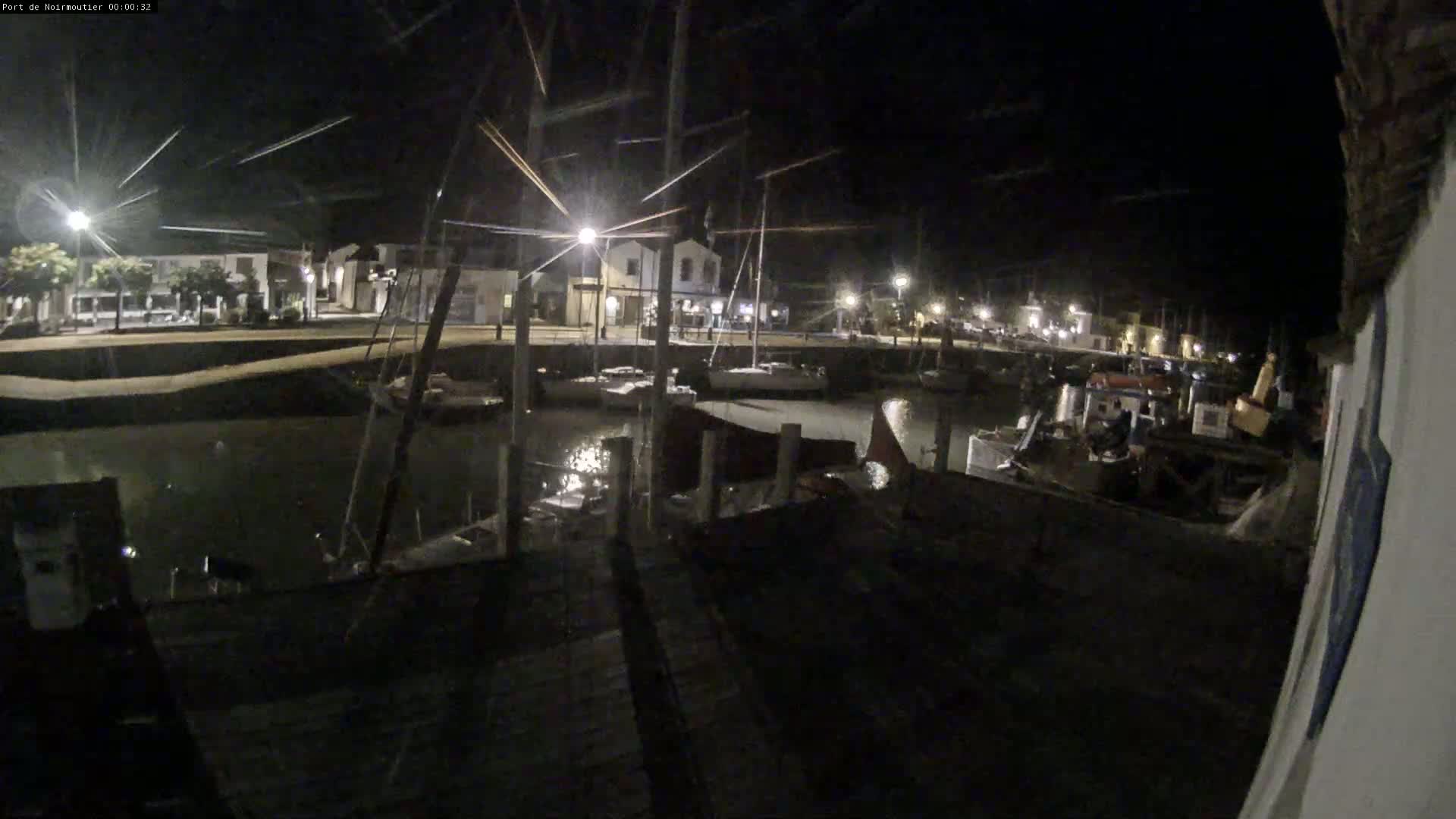 A nighttime view of a harbor filled with boats moored at docks near a town with streetlights.