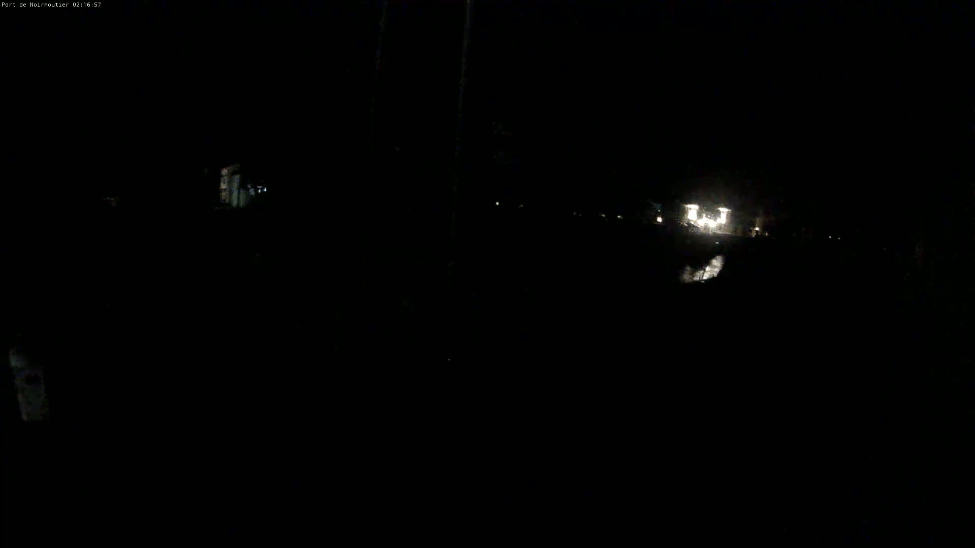 A dark, nighttime scene shows dimly lit structures and faint lights in the distance.