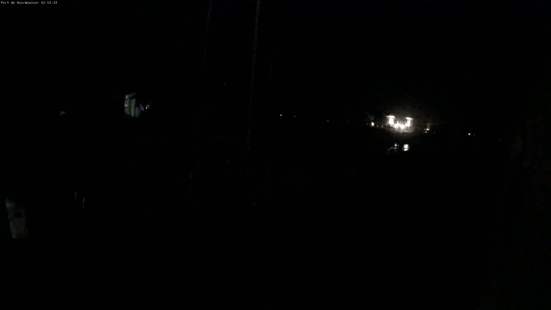 A nighttime, dark outdoor scene shows a few faint lights in the distance.