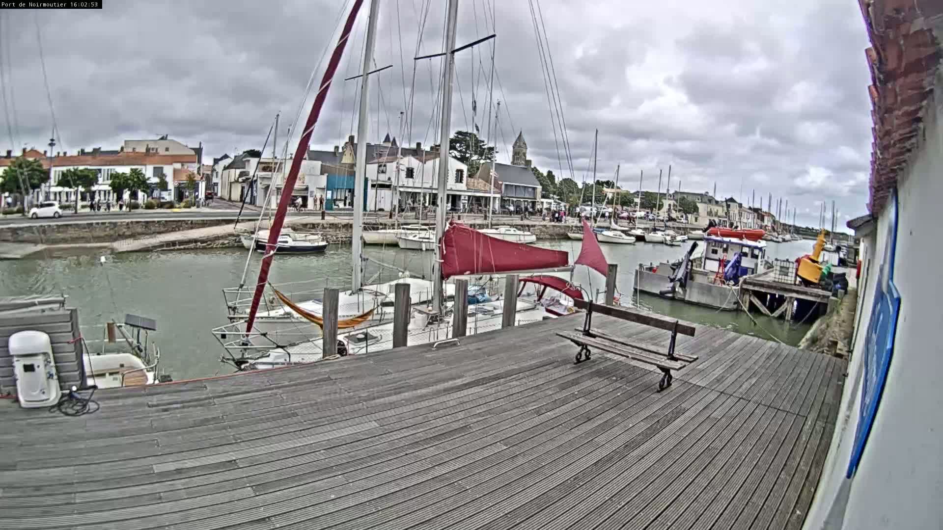 A harbor with numerous sailboats and small vessels docked under a cloudy sky.