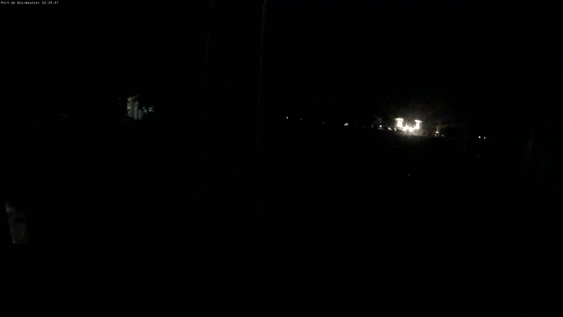 A nighttime, low-light view shows faint lights in the distance on a dark road.