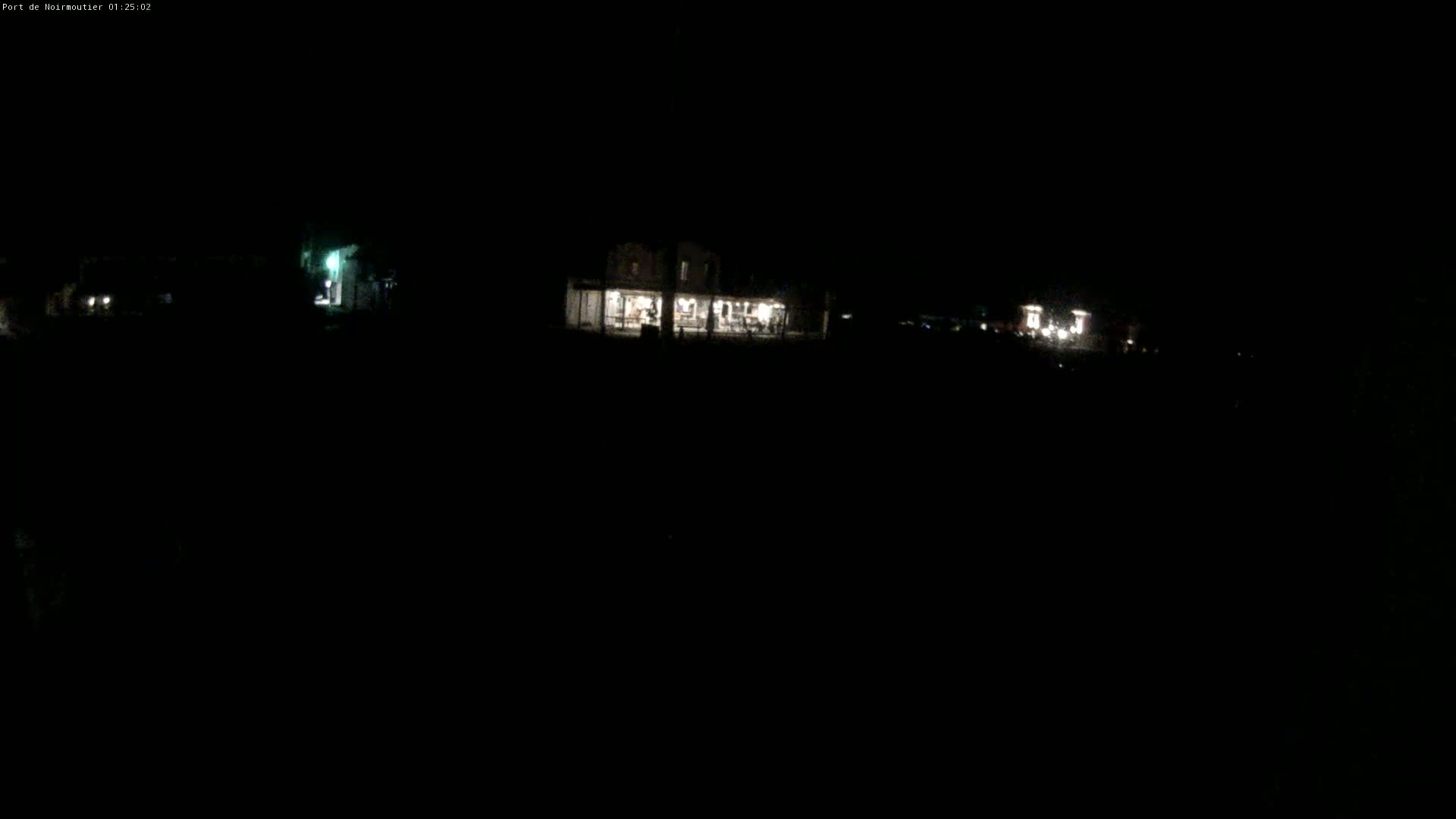 At night, a dimly lit building is visible in the distance, with other faint lights scattered around it.