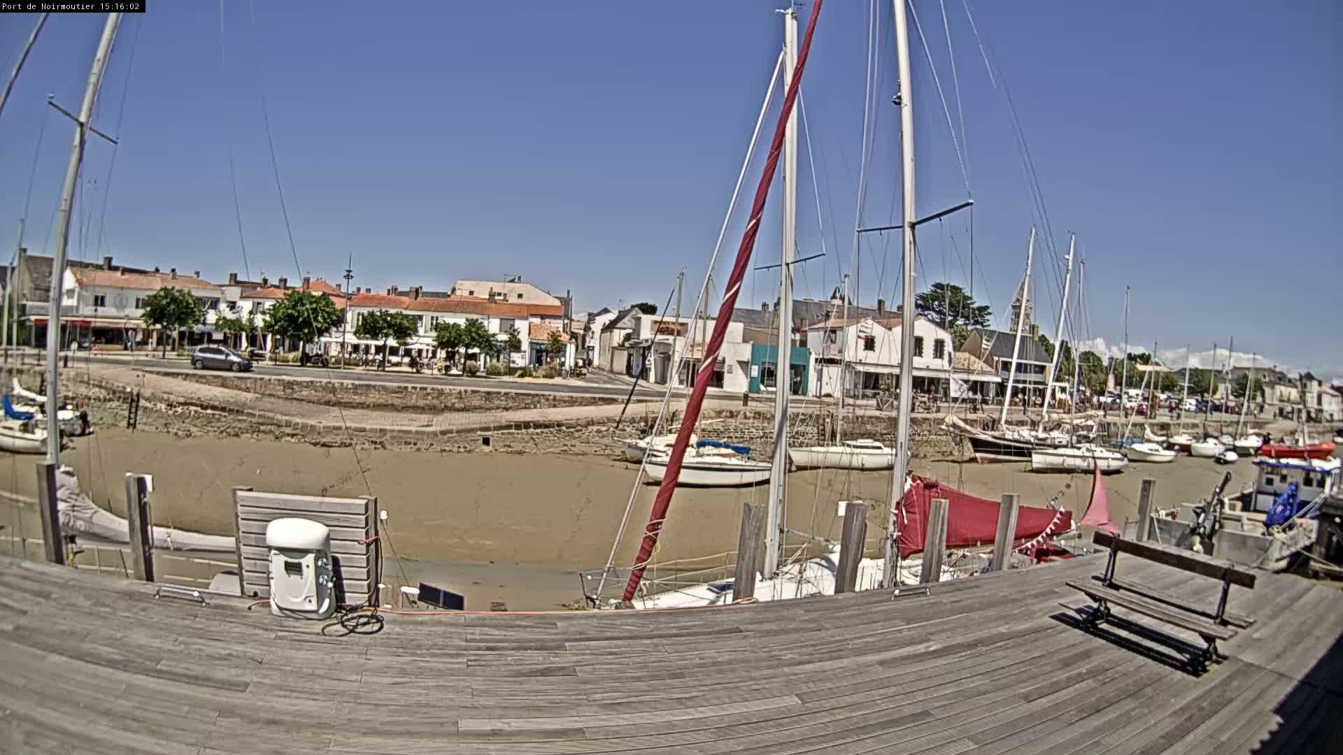 A harbor with sailboats moored at low tide on a sunny day.