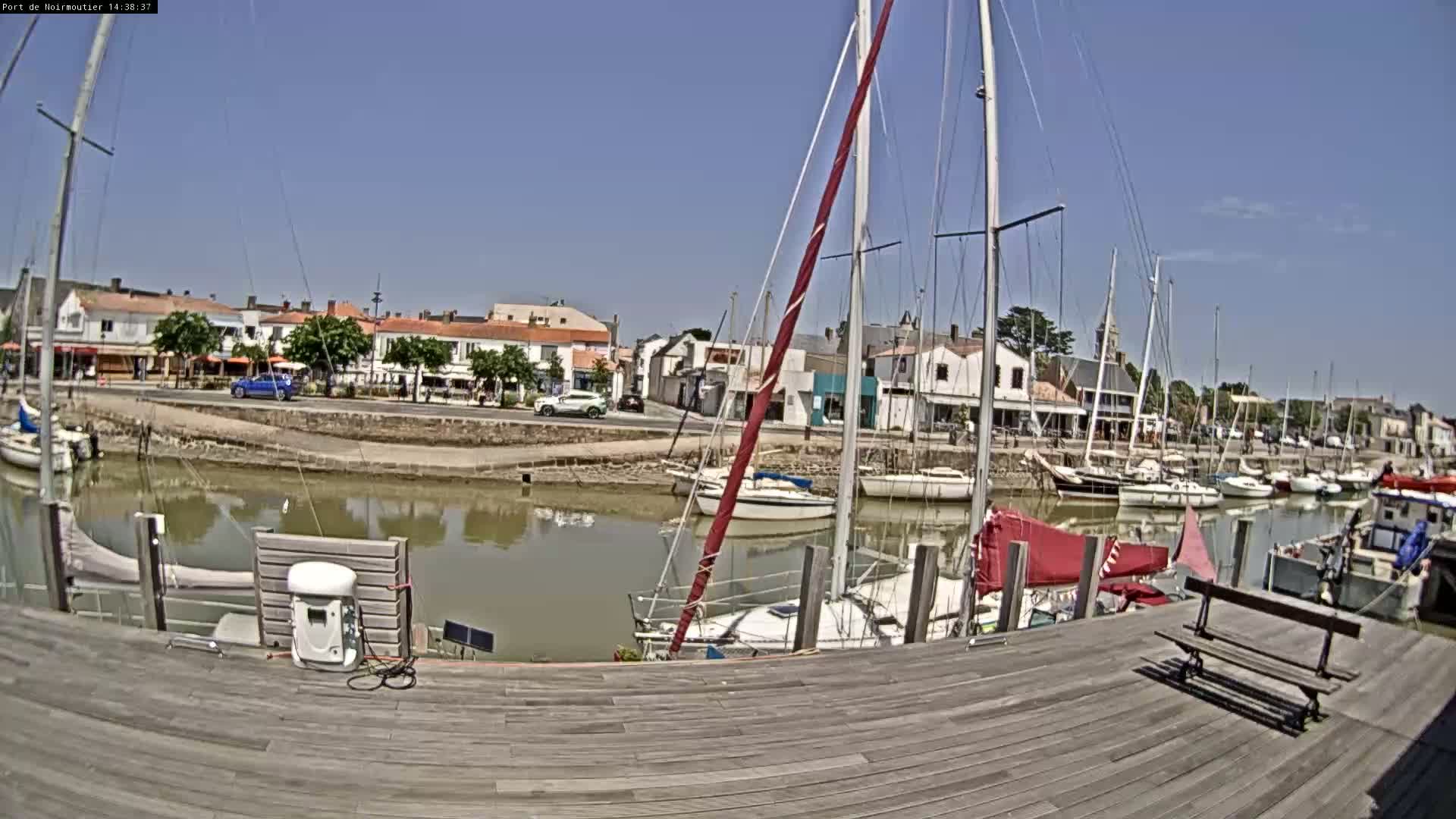 A harbor filled with sailboats on a sunny day, with a small town visible across the water.