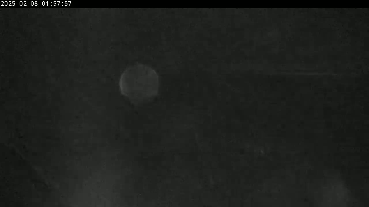 A blurry, out-of-focus image shows a bright, circular light source in a dark, nighttime setting.