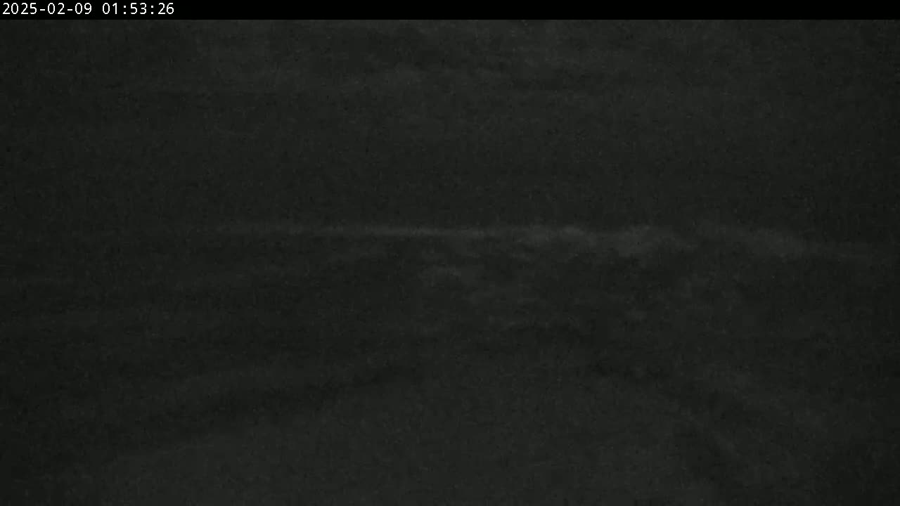 A dark, nighttime image shows a faint, horizontal band of lighter gray across a mostly black background.