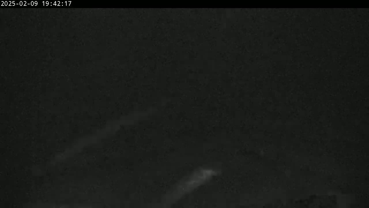 A dark nighttime scene shows faint, blurry streaks of light in the sky.
