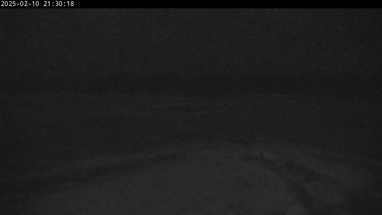 A dark, nighttime image shows a mostly featureless, dark gray and black landscape.