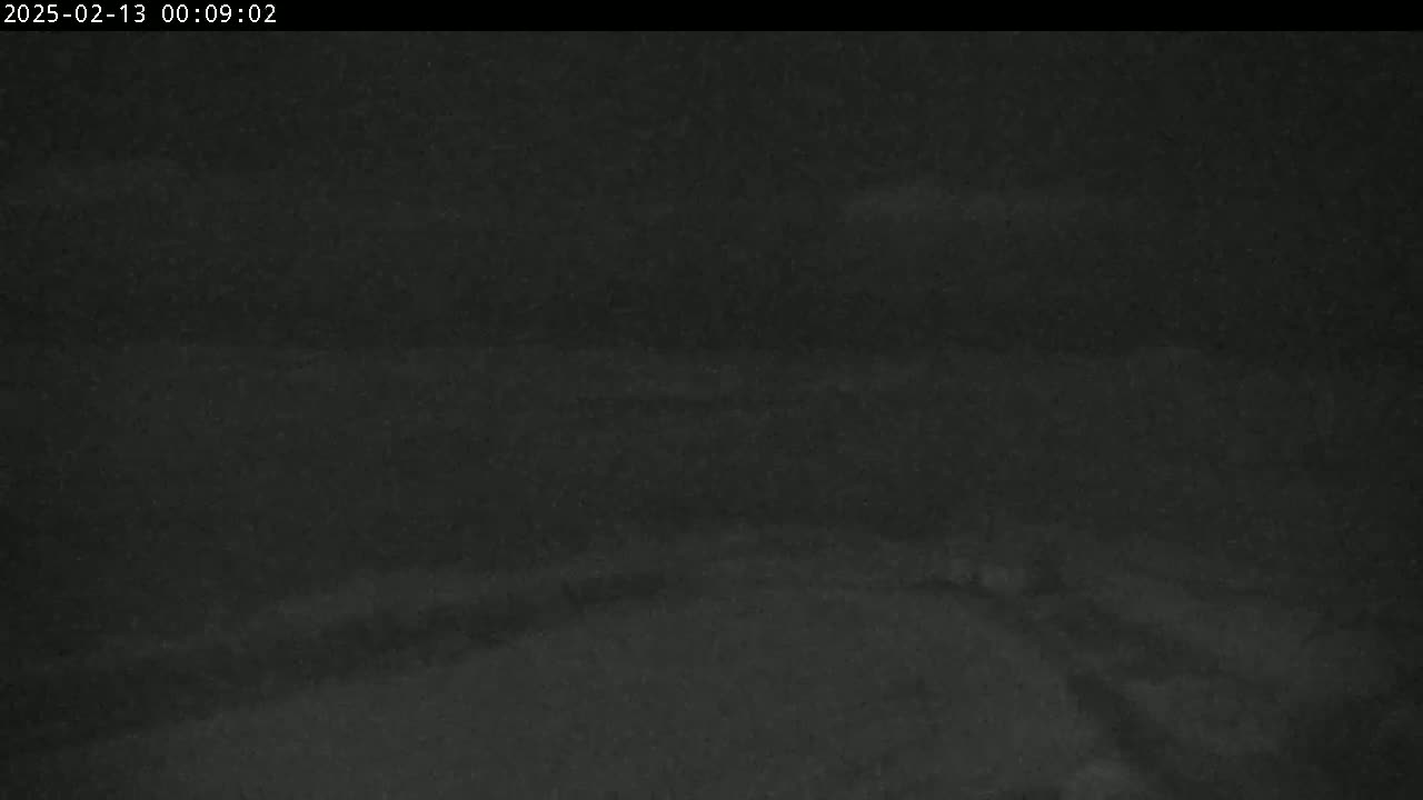 A dark, blurry nighttime image shows a snow-covered, possibly road-like surface.