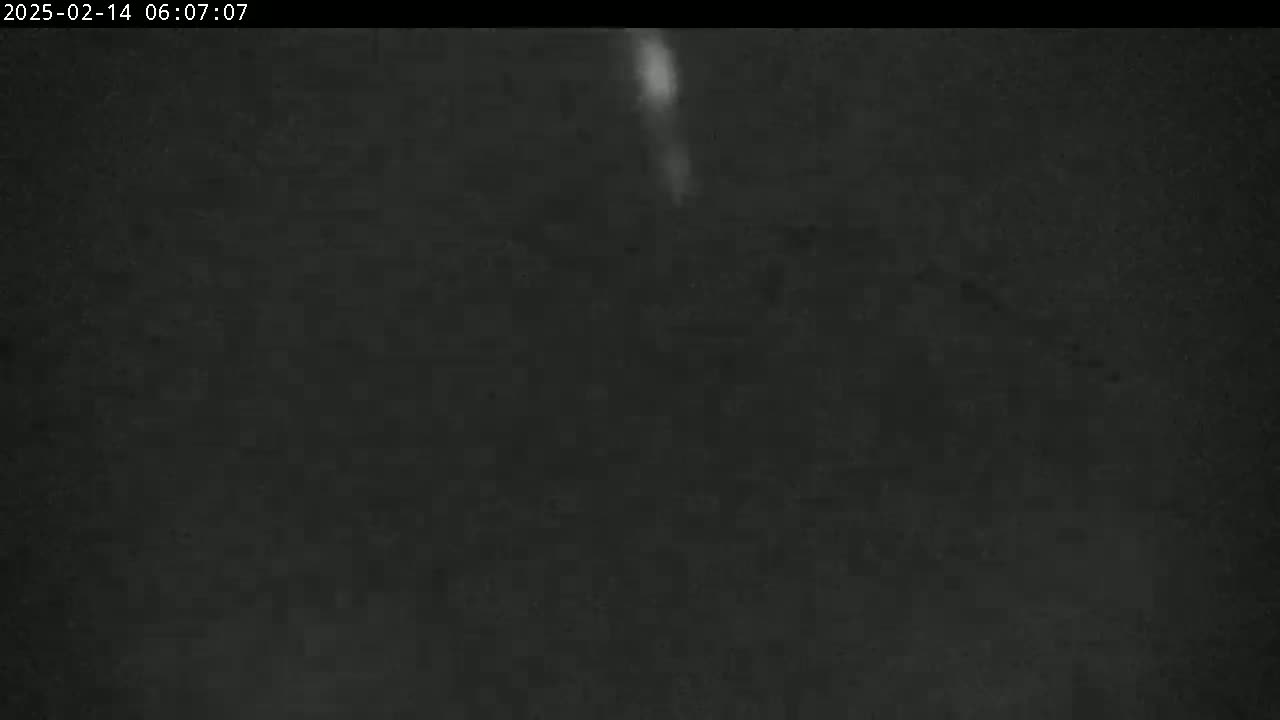 A dark, nighttime scene shows a faint, vertical streak of light in the center.