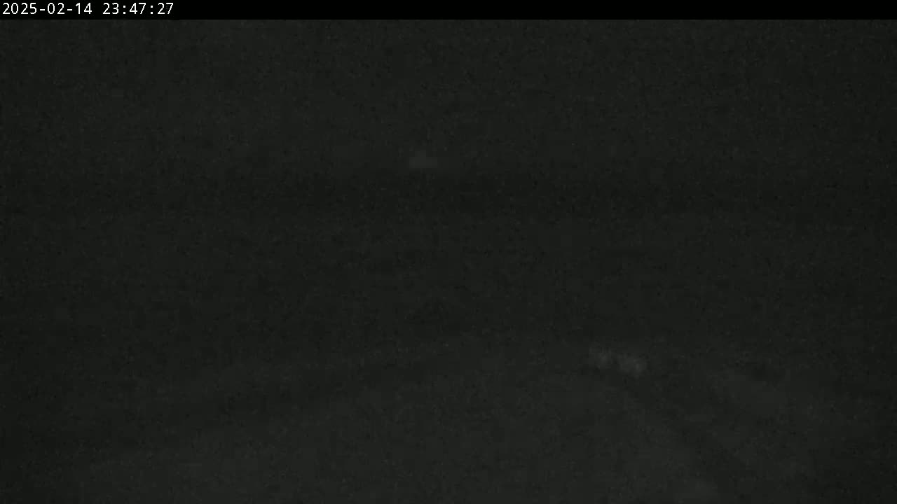 A dark, possibly nighttime, scene shows a very low-light, grainy image with indistinct shapes and minimal visible detail.