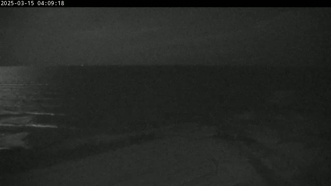 A dark, nighttime view of a body of water with a relatively calm surface.