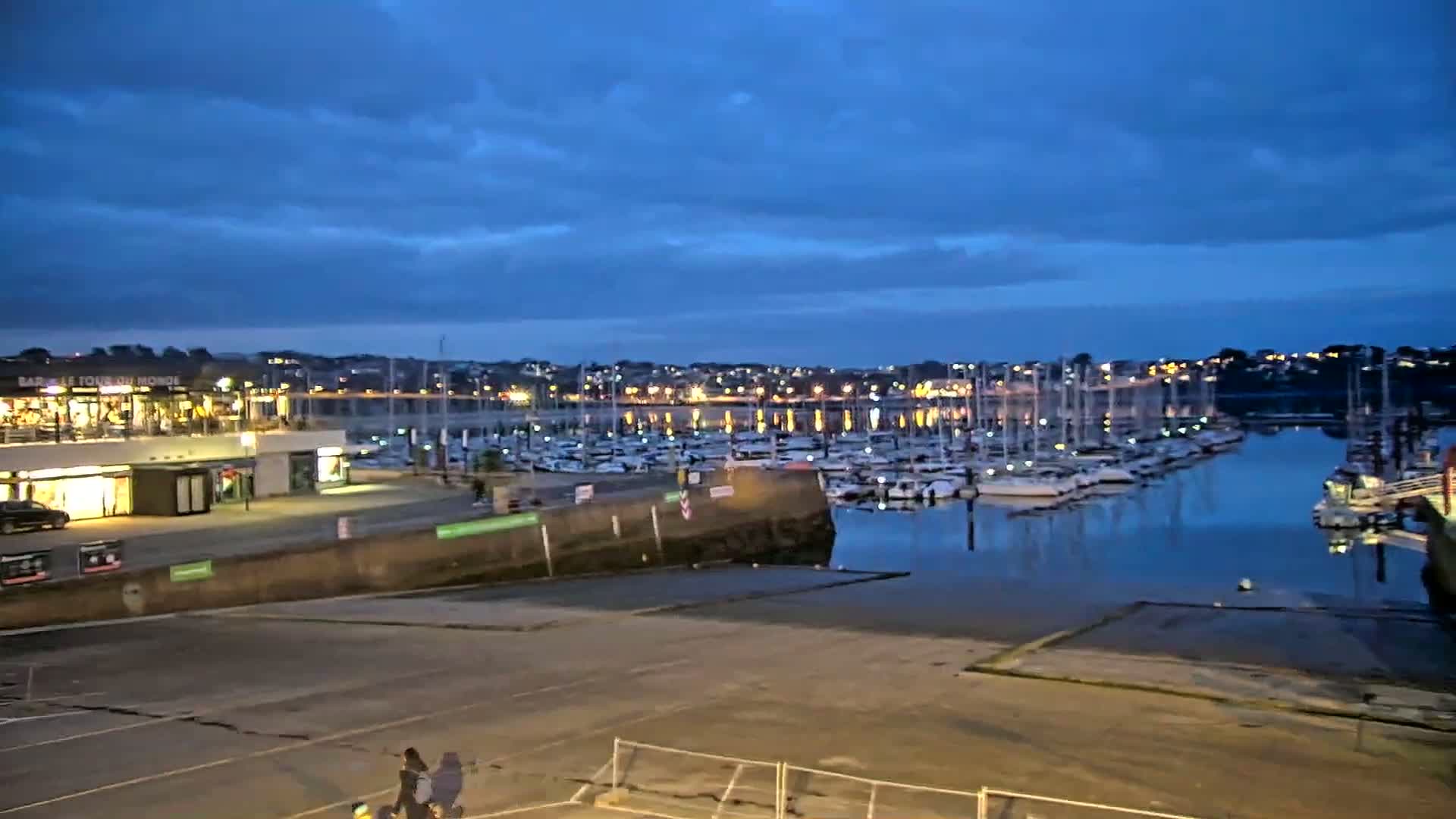 A marina filled with boats at twilight under a partly cloudy sky.