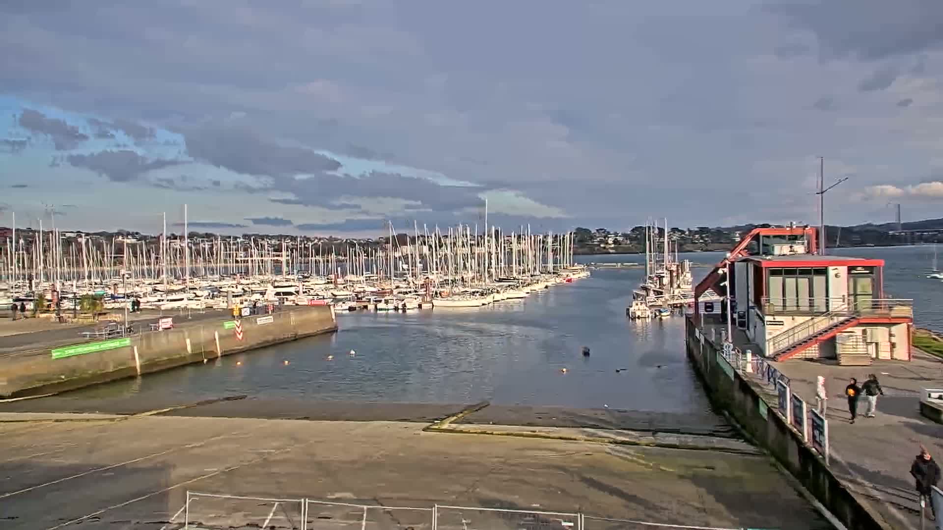 A marina filled with sailboats under a partly cloudy sky.