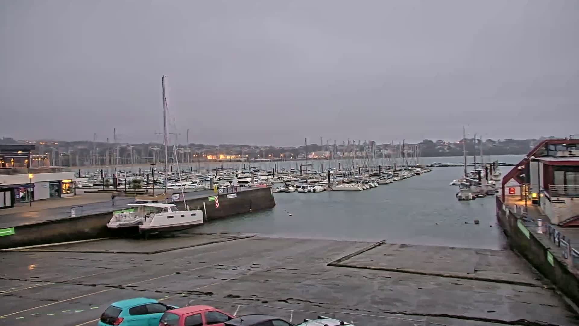 A marina filled with numerous sailboats and motorboats under an overcast sky.