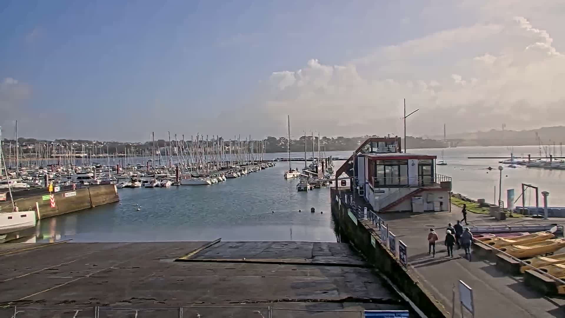 A marina filled with sailboats under a partly cloudy sky.
