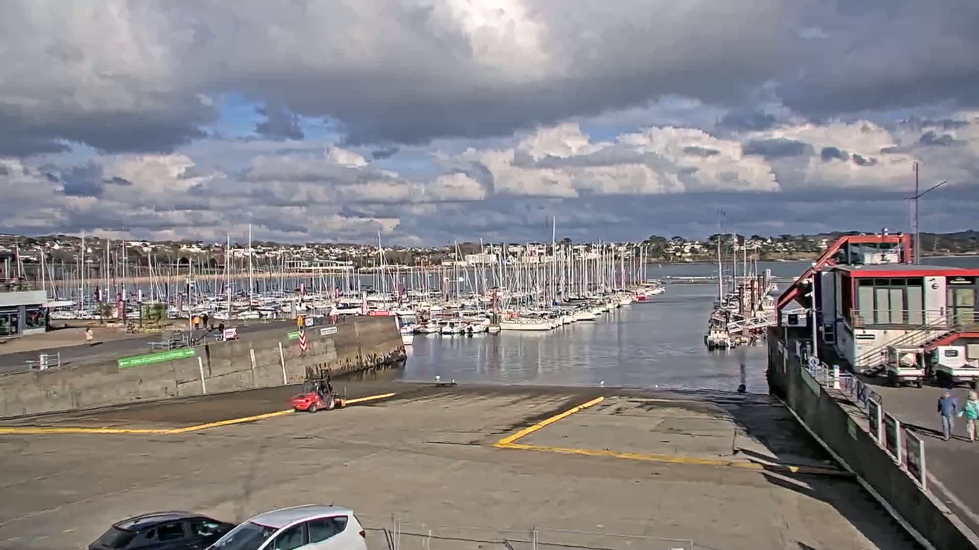 A harbor filled with sailboats under a partly cloudy sky.