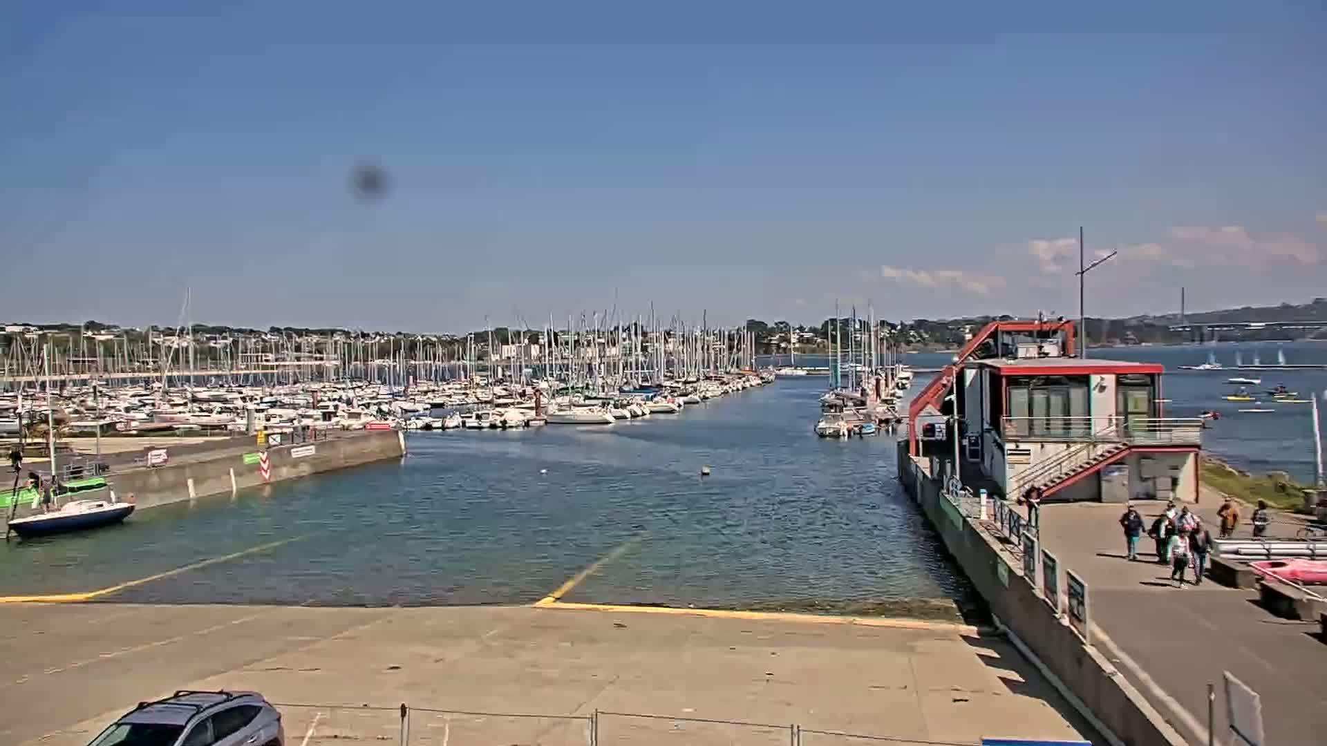 A marina filled with sailboats on a sunny day, with a few people walking along the dock.