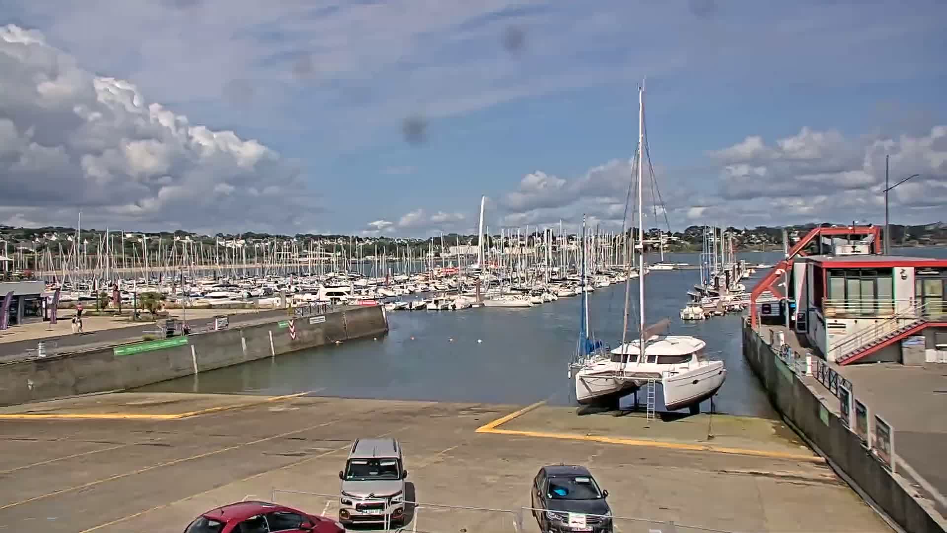 A marina filled with numerous sailboats and motorboats under a partly cloudy sky.