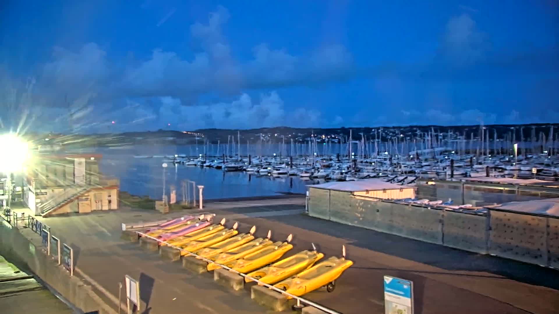 A marina filled with numerous sailboats and motorboats under a partly cloudy sky.