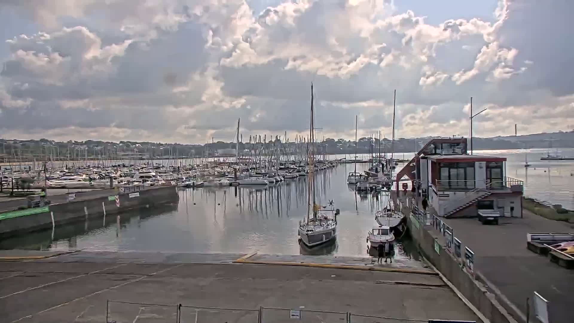 A marina filled with numerous sailboats and motorboats under a partly cloudy sky.