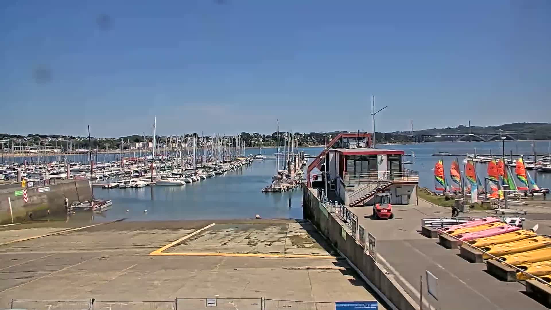 A marina with numerous sailboats and several small sailboats and kayaks docked on a sunny day.