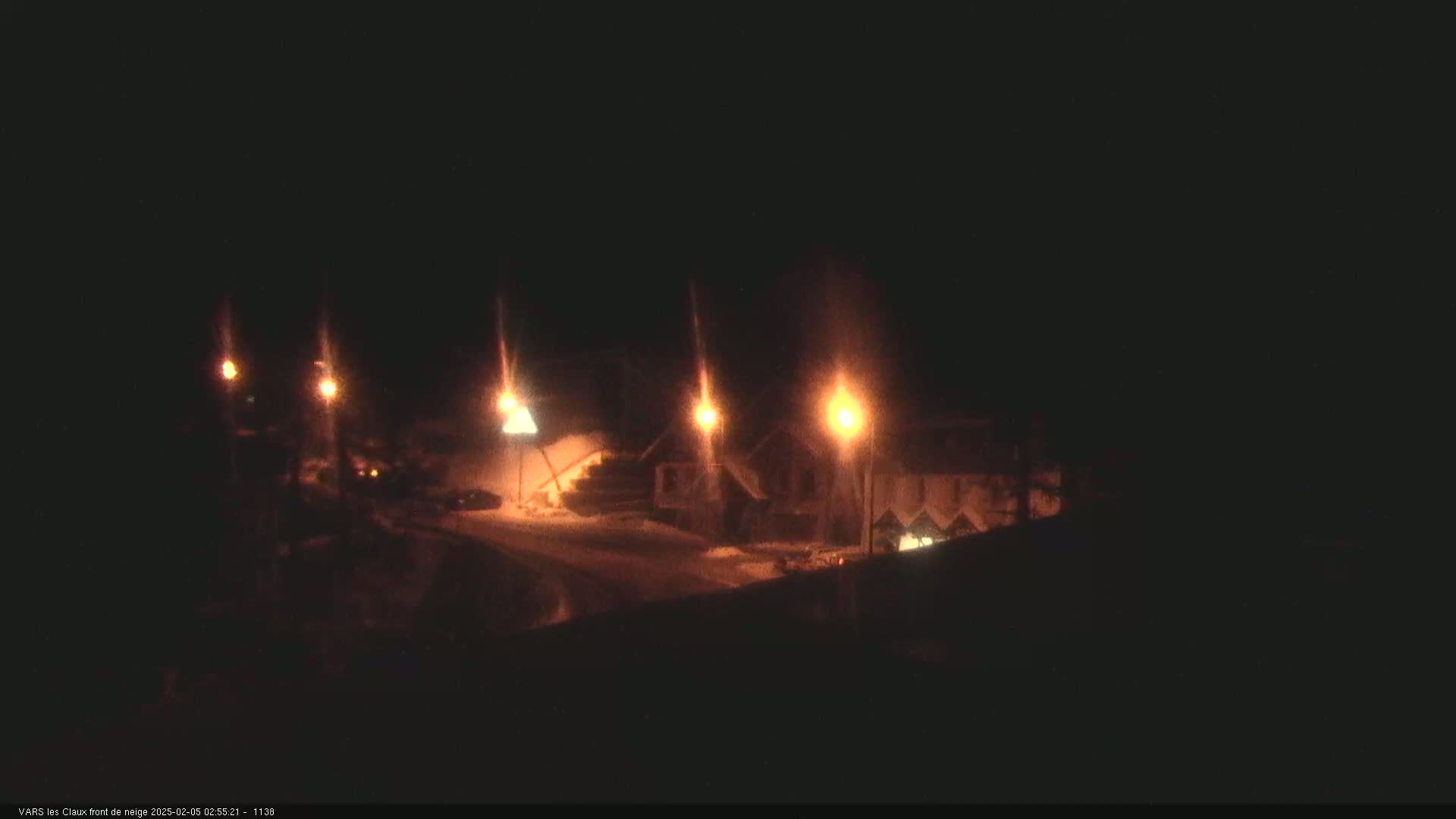 Several illuminated buildings are visible at night in a snowy setting.