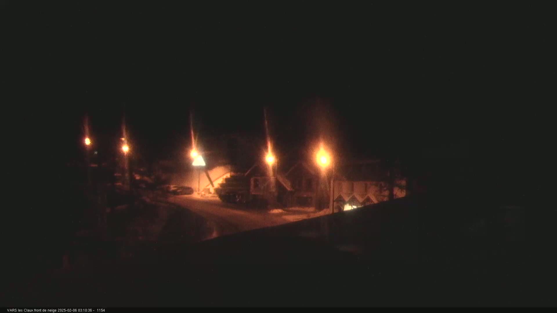 At night, several illuminated buildings are visible in a snow-covered area, lit by streetlights.