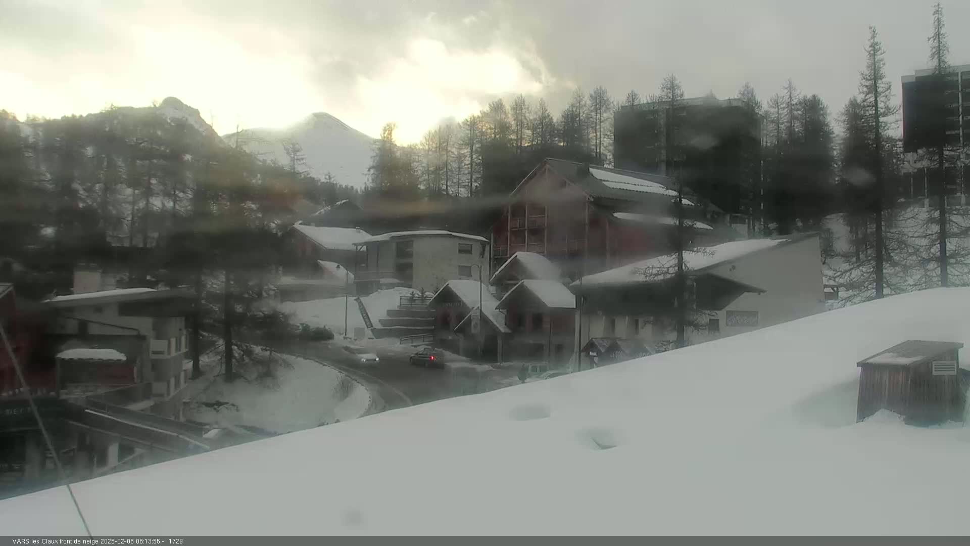 A snow-covered village nestled in a mountain valley under a cloudy sky.