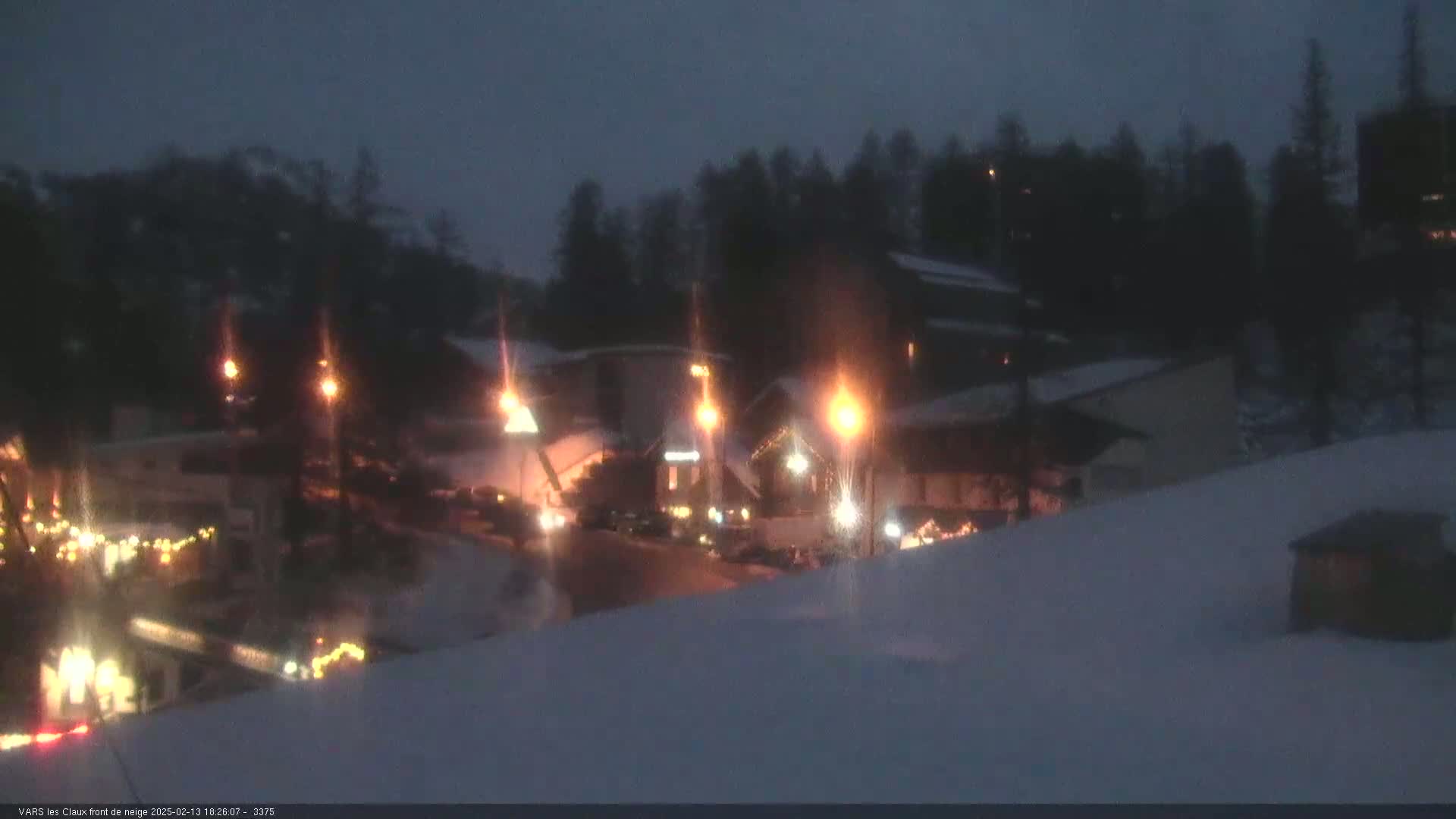 A snow-covered village at night, illuminated by streetlights and building lights.