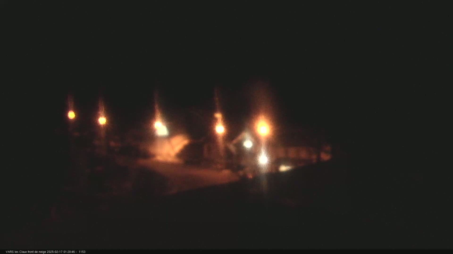 Several blurry lights illuminate a dark, nighttime scene, possibly a road or parking lot.