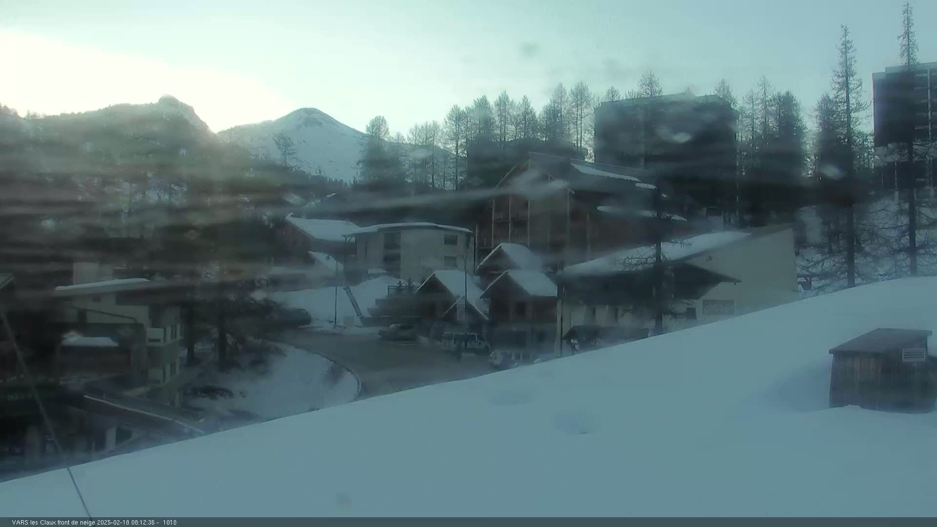 A snow-covered village nestled in a mountainous region under a hazy sky.