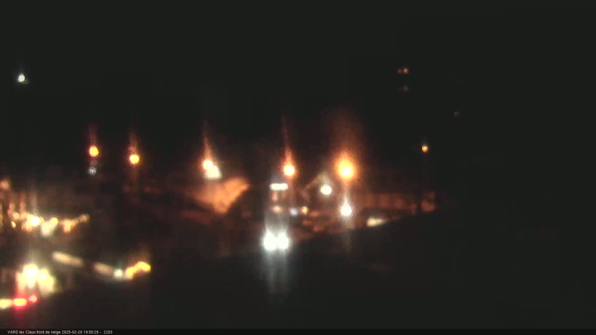 A nighttime, blurry view of a road with several indistinct vehicles and streetlights.