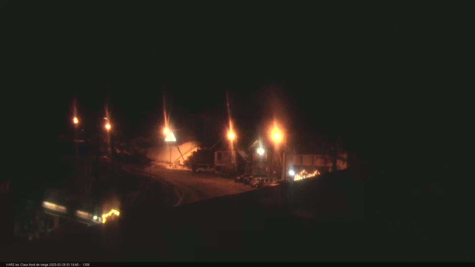 At night, several illuminated buildings and streetlights are visible in a snowy, dark scene.
