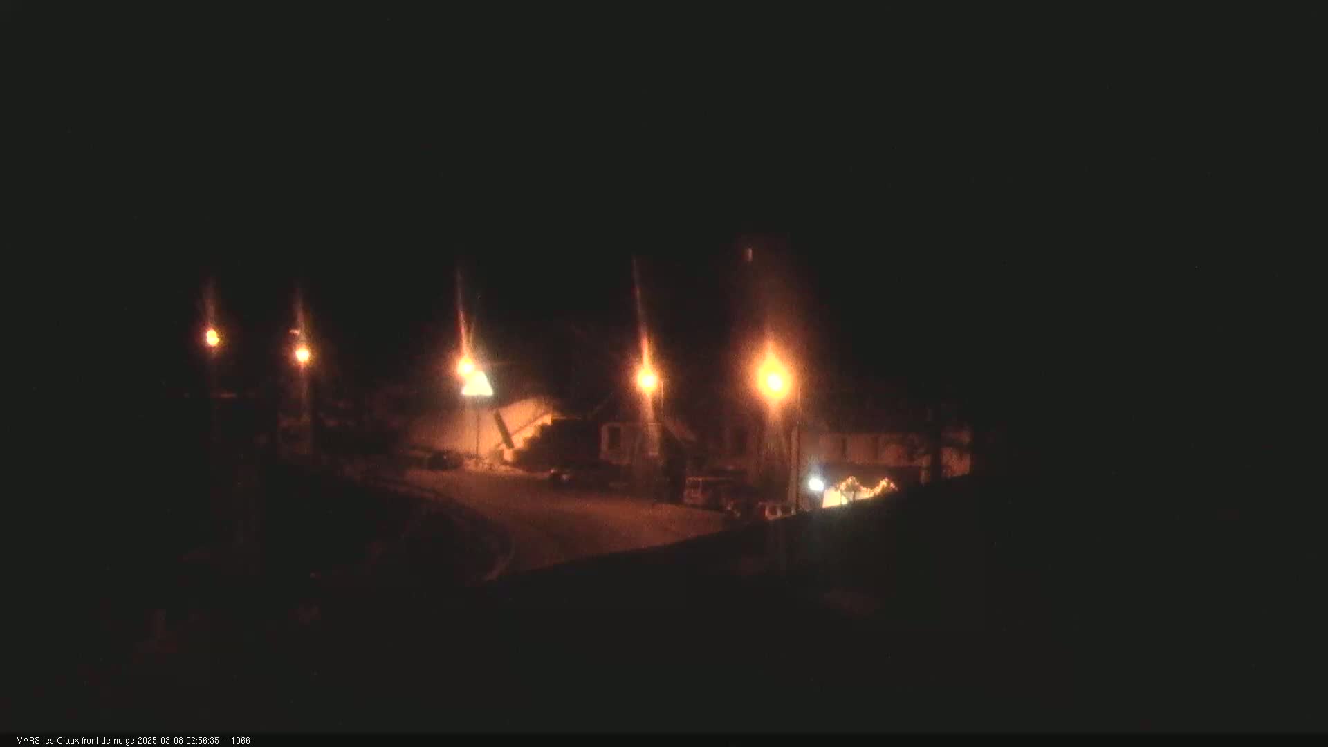 At night, several illuminated buildings and streetlights are visible in a dimly lit area.