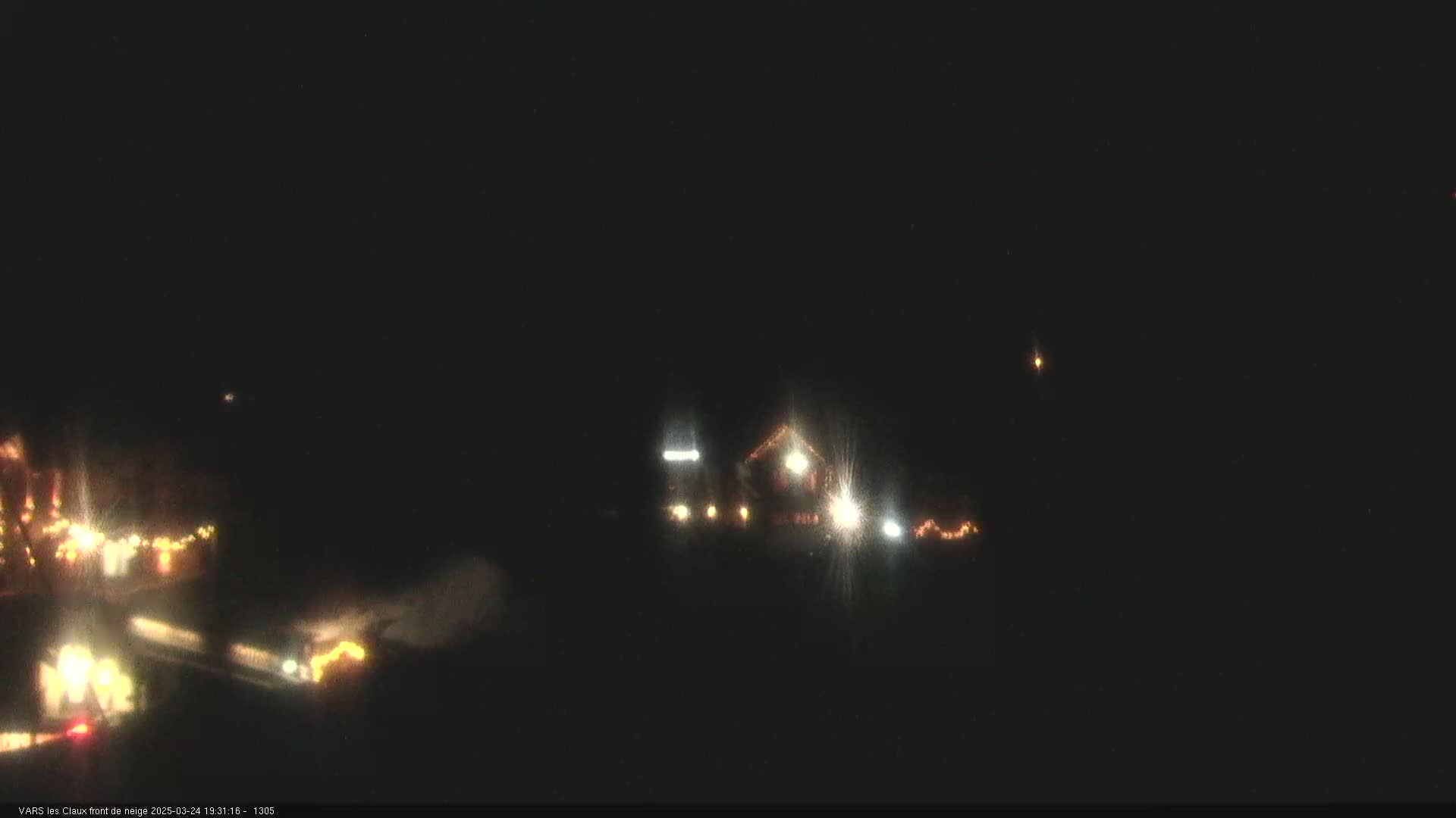 At night, a dimly lit building and some vehicles are visible, with a dark sky above.