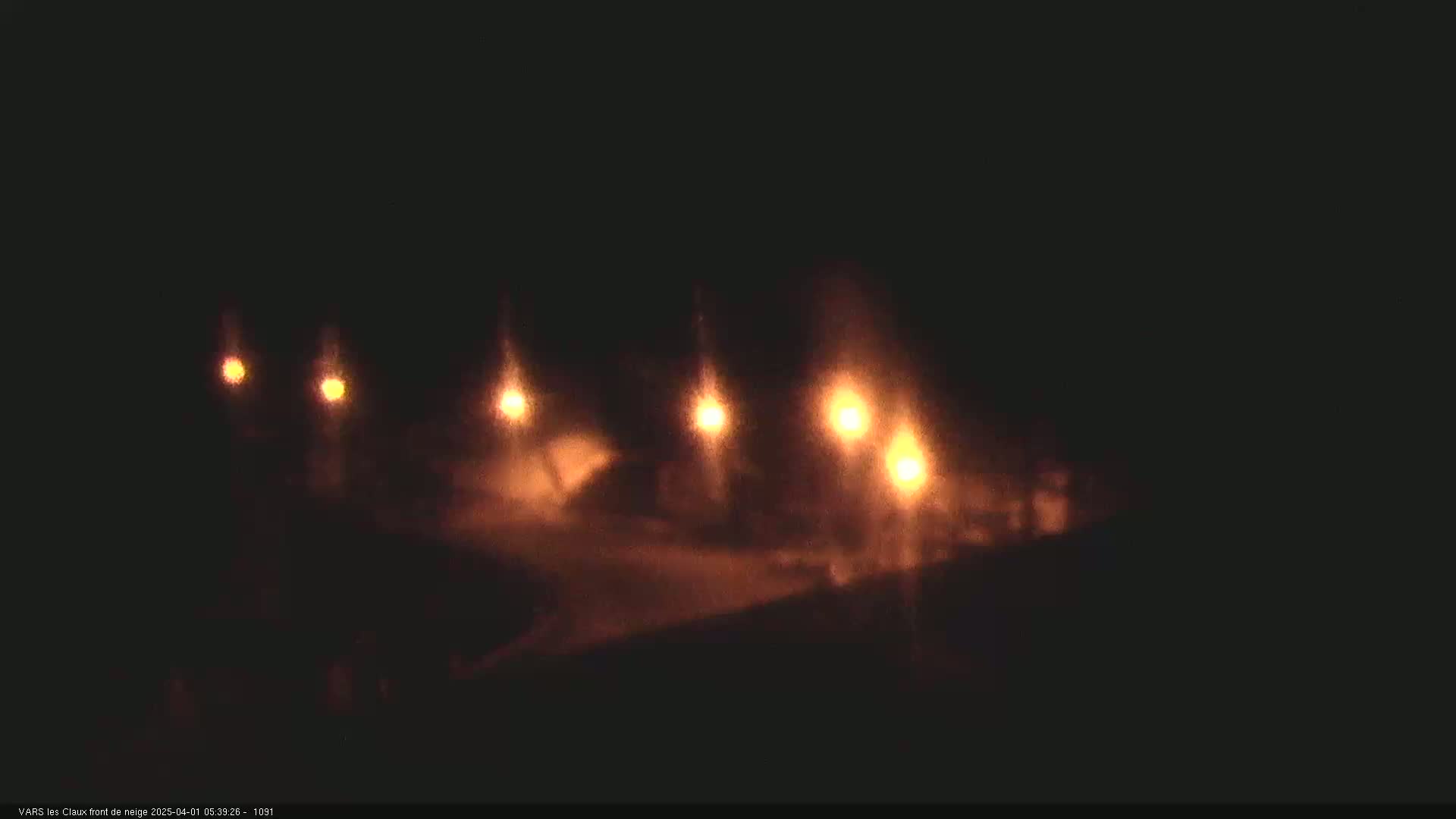 Several sets of vehicle headlights are visible on a dark road at night.