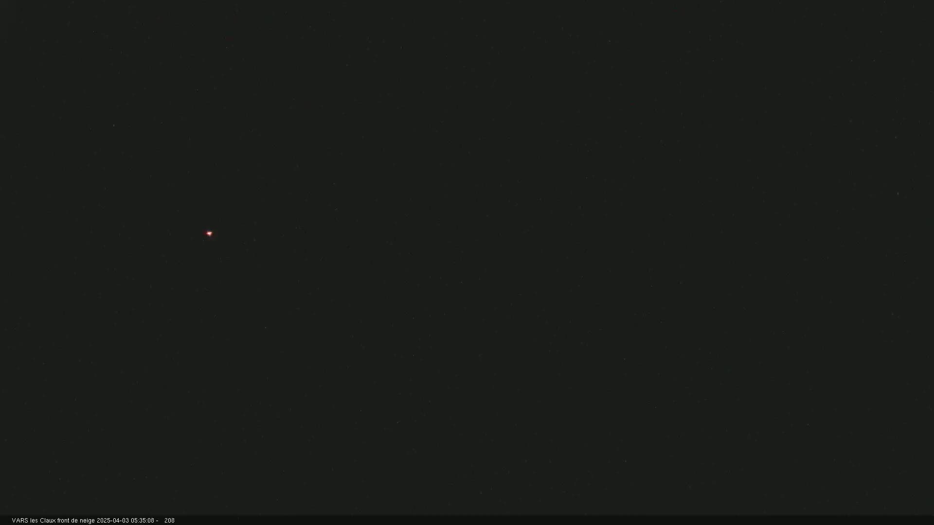 A small, faint reddish light is visible in a dark, nighttime sky.