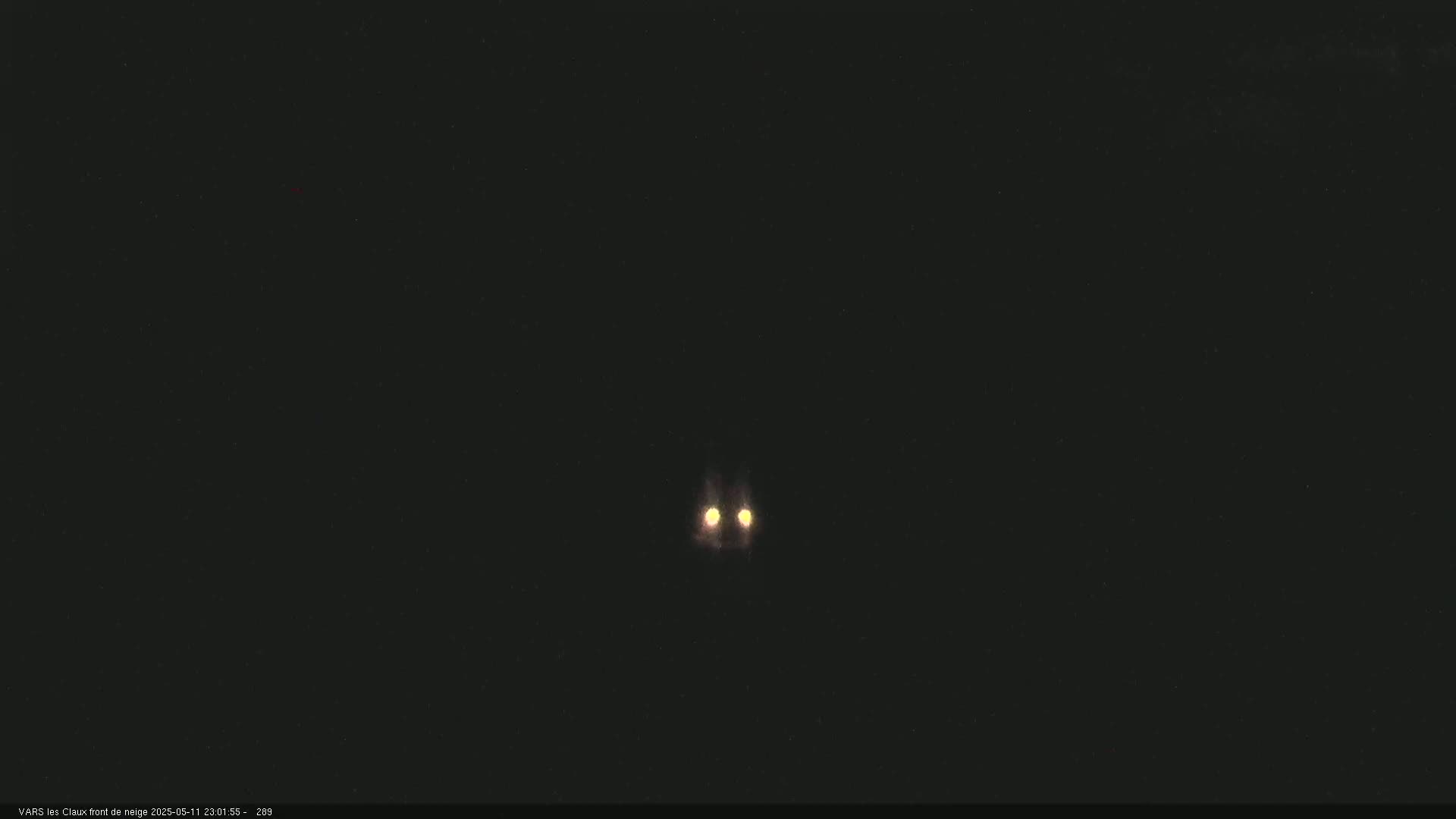 A pair of bright lights are visible in the dark night sky.